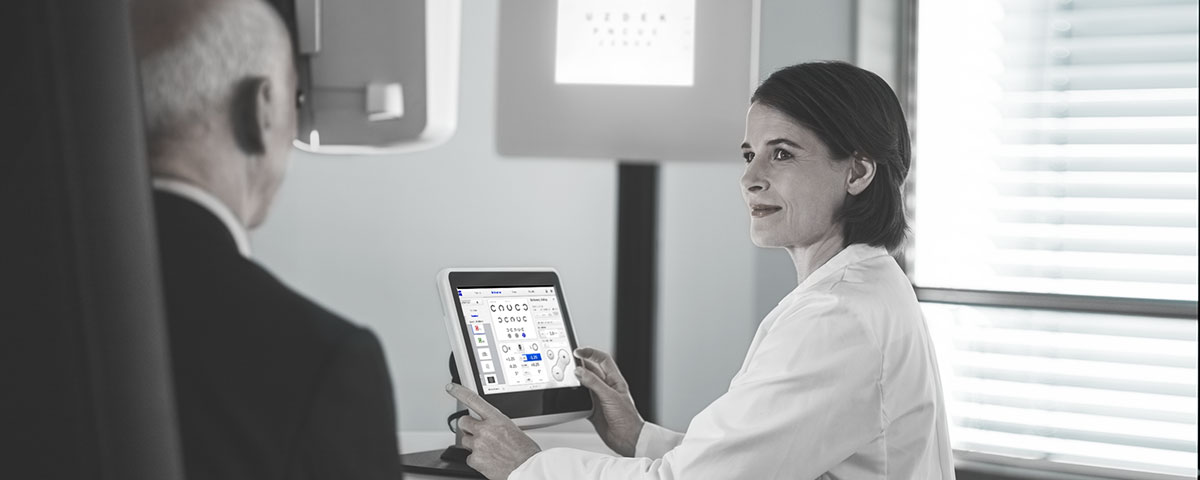 Optikerin bei der Arbeit, mit Blick auf einen Patienten ein Zeiss Interface bedienend